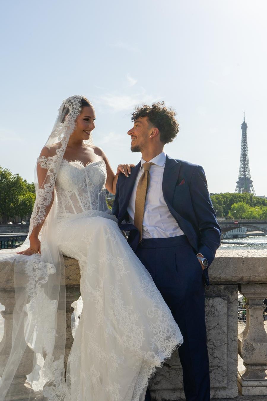 Mariés souriants sur un pont, tour Eiffel en arrière-plan